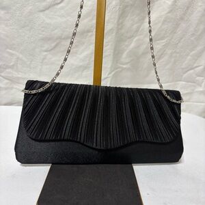 black pleated evening clutch bag with a detachable silver-tone chain strap.